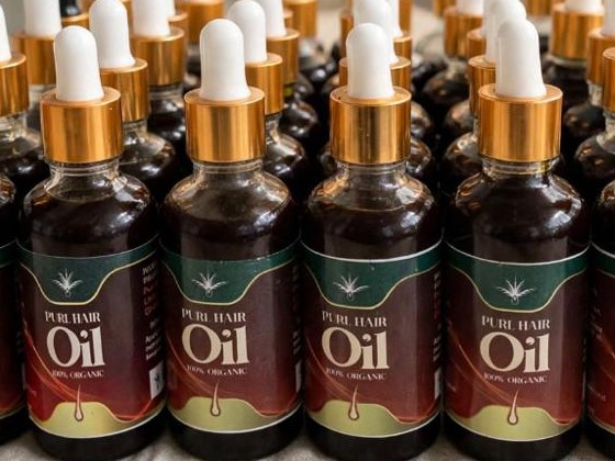 Close-up of Purl Hair Oil bottles with green and maroon labels and gold caps